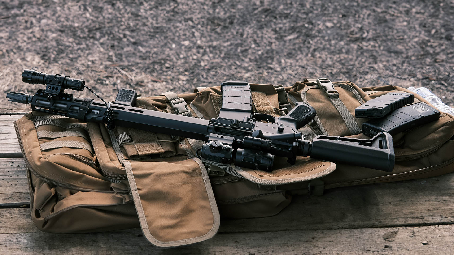 AR-15 and two extra magazines lying on a range bag