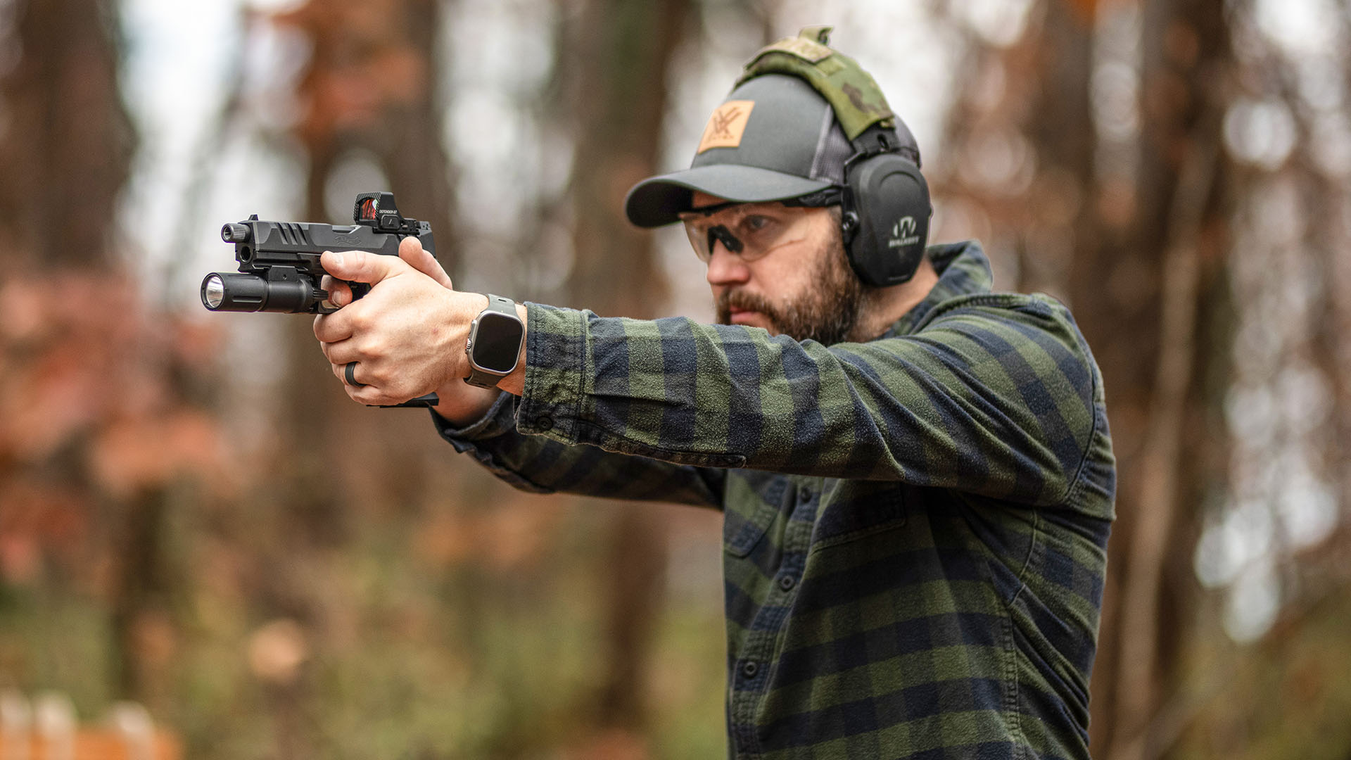 man aiming a gun at an outdoor range