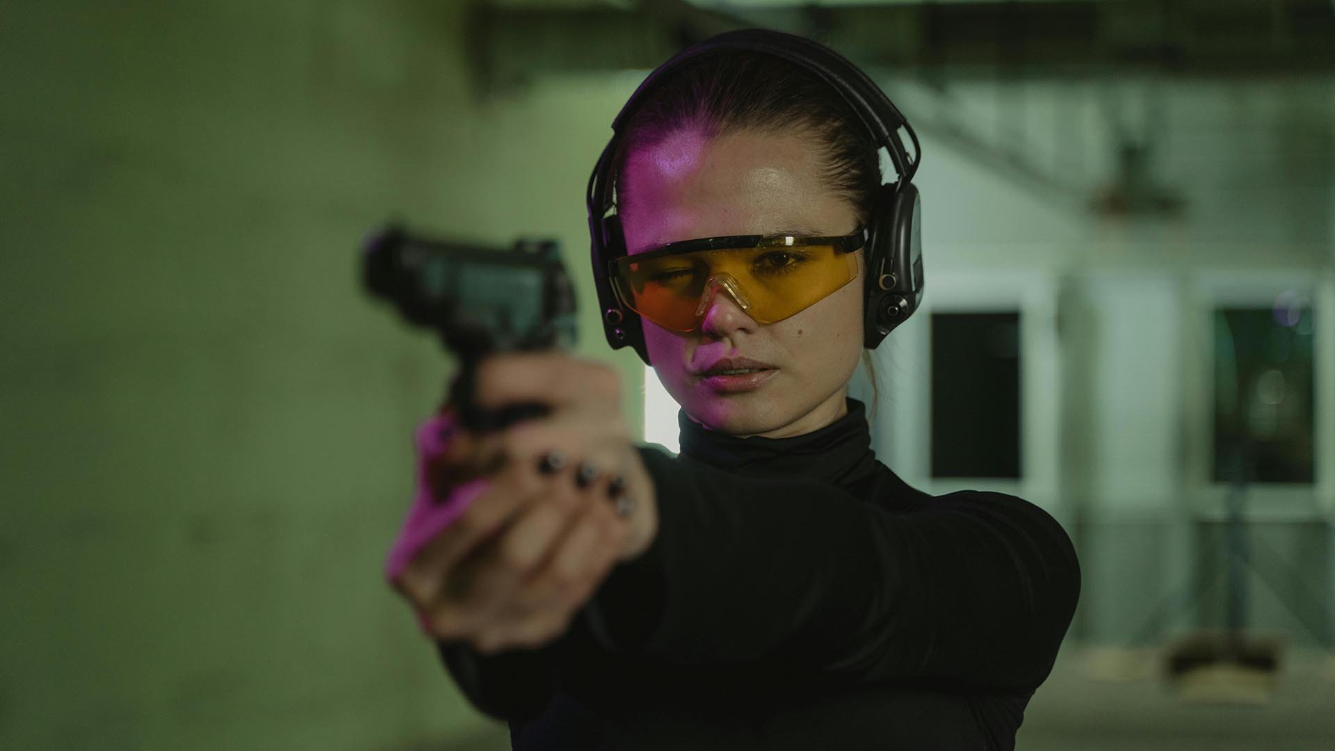 woman aiming handgun at a range
