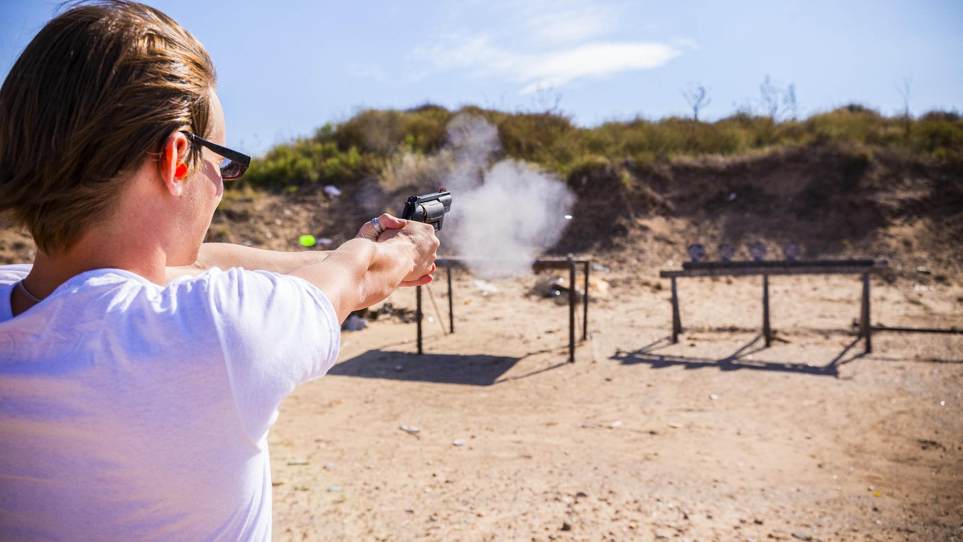 woman shooting a gun at a metal target